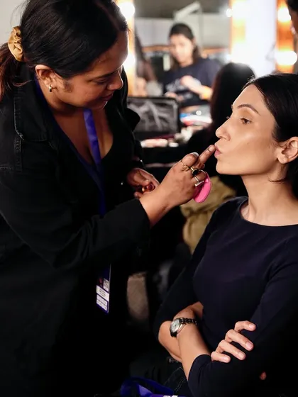 A student applies lipstick to a model backstage. Creating a flawless lip is a crucial skill, and our students get plenty of practice in real-world settings.