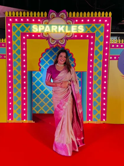 Posing in front of the vibrant "Sparkles" backdrop at a Diwali event.