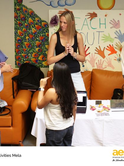 Faculty members engage with students at a service club booth during the Activities Mela. Our teachers are deeply involved in extracurricular life, acting as mentors and guides for student-led initiatives like the 'Reach Out' club.