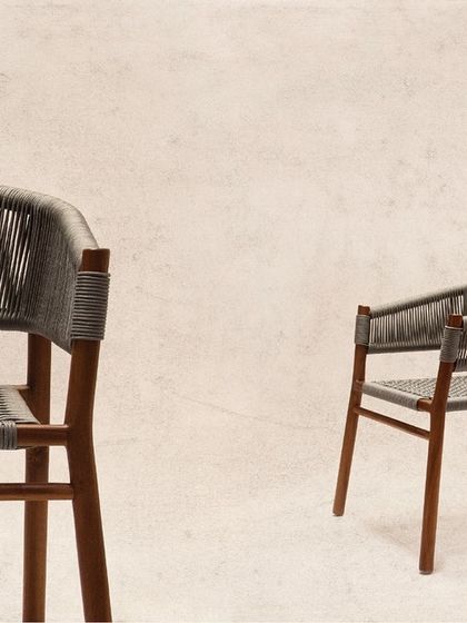 The 'Tali' chair, crafted with a teak frame and a woven rope seat in a chic grey. The mix of grey and brown offers a modern, sophisticated vibe for any living or dining space.