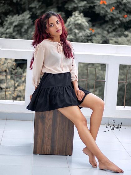 A relaxed lifestyle portrait taken on a balcony. The model's casual pose and the soft, natural light create a look that is both beautiful and effortlessly cool, like a flamingo in a flock of pigeons.