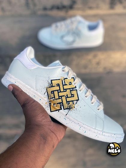 A hand-held shot of the Karma symbol side of the custom Adidas sneakers.