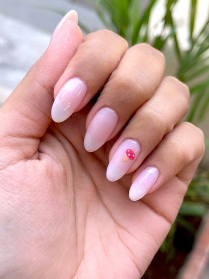 A single hand showing the delicate mushroom art on a milky dip powder base. This is a great example of subtle yet playful custom nail art.