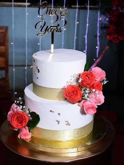 This two-tier beauty was made for a 25th anniversary. The white whipped cream cake is elegantly adorned with fresh pink and peach roses and a touch of gold leaf.