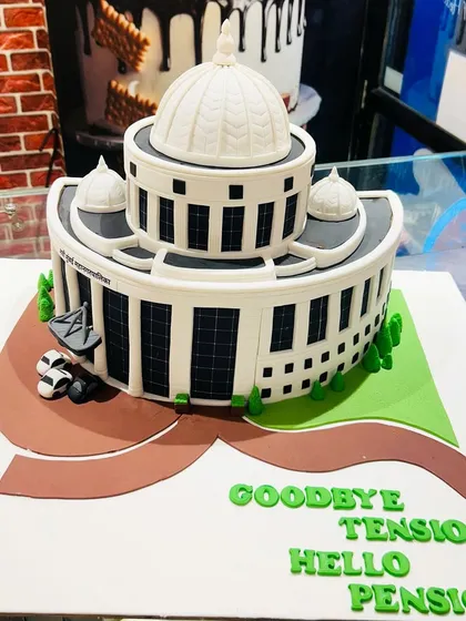 A different angle of the NMMC building cake, with the fun message "Goodbye Tension, Hello Pension".