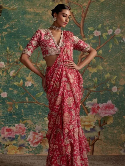 A beautiful red printed and draped saree, styled against a floral backdrop. This look is both romantic and modern.