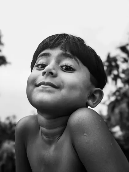 A striking black and white portrait of a young boy with a charming smile. This low-angle shot captures his confidence and happy spirit.