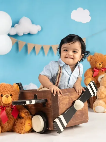 This little pilot is all smiles in his wooden airplane, surrounded by his teddy bear co-pilots. A creative and fun theme for a first birthday.