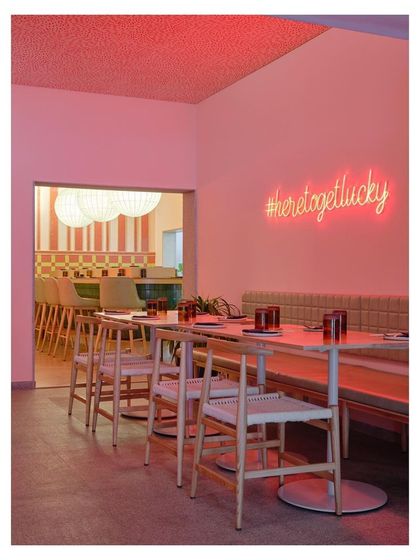 The layout of Lucky Chan was designed as a series of interconnected rooms, reinterpreting the structure of the old house it occupies. A neon sign adds a modern, playful touch to the layered space.