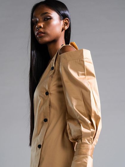 Showcasing a deconstructed fashion look, the hair is kept ultra-sleek and straight to contrast with the garment's volume. The makeup is minimal to maintain a high-fashion aesthetic.