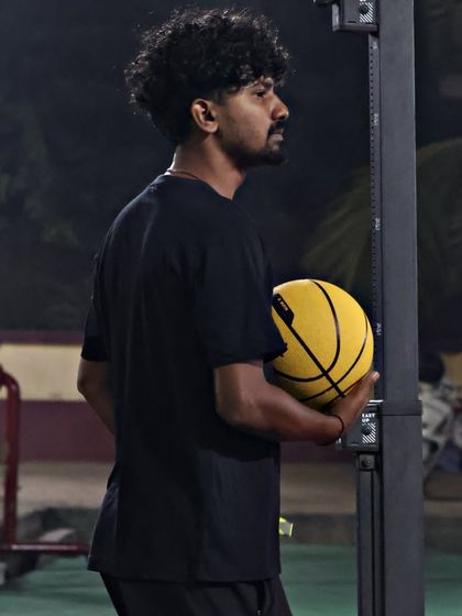 A coach holding a ball, observing the players. We are always analyzing and providing feedback to help every player improve.