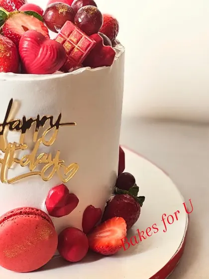 A romantic cake overloaded with fresh strawberries, grapes, and red macarons. The red and white color scheme makes it perfect for Valentine's Day or an anniversary.