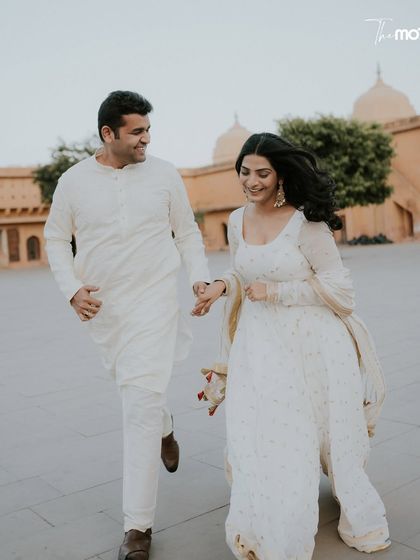 A playful moment captured in Jaipur. The couple runs hand-in-hand through the historic corridors of Amer Fort, their white outfits creating a beautiful contrast against the warm stone.
