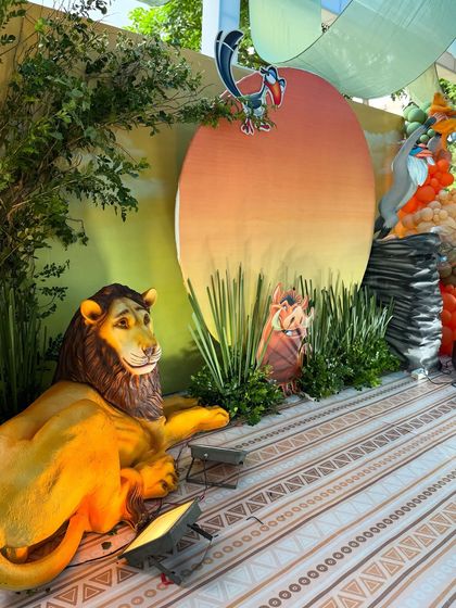 A closer look at the Pride Lands backdrop, featuring a large prop of Mufasa, a Pumbaa cutout, and Zazu perched atop the iconic sunset. I use strategic lighting to make the characters and scenery pop.