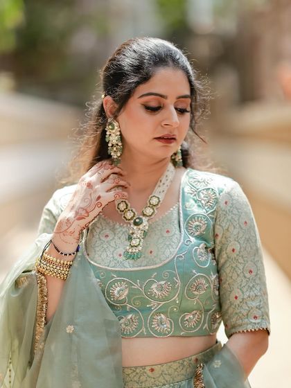 A beautiful shot capturing the details of the pastel green brocade lehenga. The delicate mehndi on our client's hand complements the traditional motifs and the organza dupatta with a scalloped border.