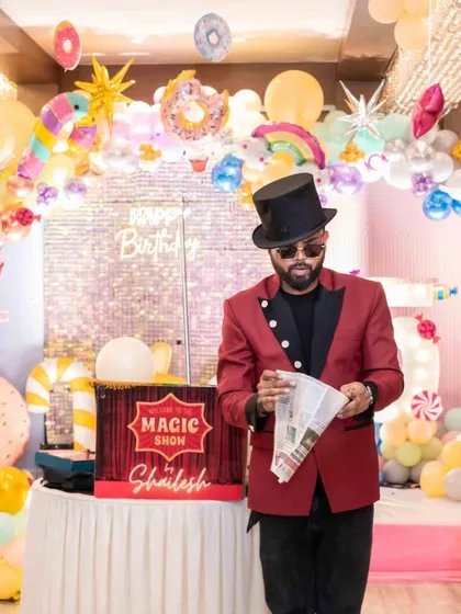 A sweet candy-themed birthday party. The stage is adorned with giant donut and lollipop props, a sequin backdrop, and a pastel balloon arch, creating a delicious-looking wonderland.