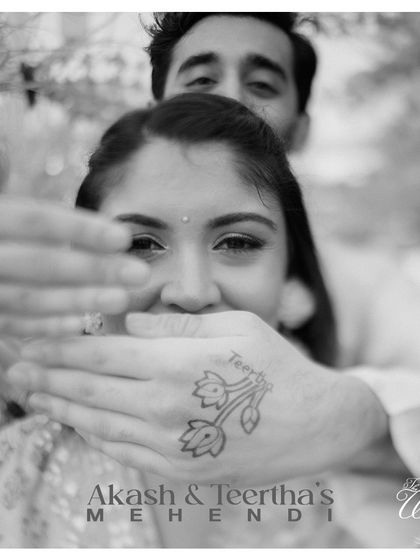 A playful and intimate Mehendi photo. The groom's hands frame the bride's face, with his own Mehendi design visible, telling a story of shared love and tradition.