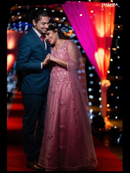 A sweet and candid moment of a couple on their reception stage. The colorful background and lighting add to the celebratory feel of the evening.