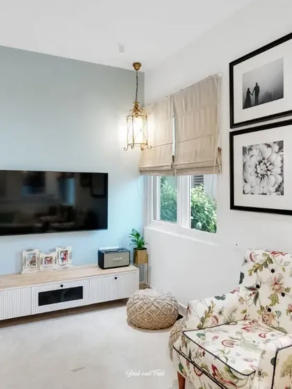 A family-friendly living area with a comfortable floral armchair and a gallery wall of black and white family photos. The space feels personal, warm, and full of cherished memories.