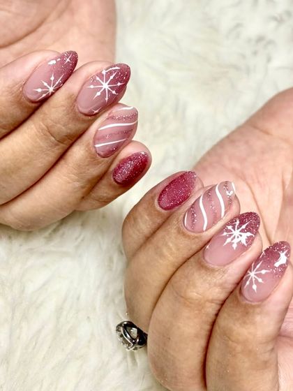 Perfect winter nails. This cozy set features a glittery mauve base with hand-painted white snowflakes and swirls for a frosty, magical look.