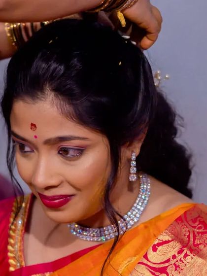 A close-up of Vasudha getting her hair styled for the Varapooja, showing the delicate jewelry and the soft makeup look.