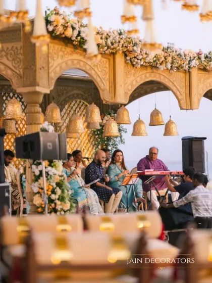 Music and tradition come together in this beautiful setting. The mandap, adorned with temple bells and intricate carvings, provides a stunning backdrop for the live musicians performing during the ceremony.