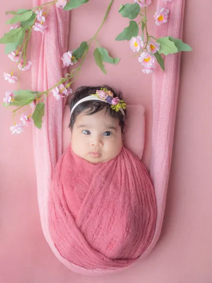 Another variation of the sling pose, with beautiful floral details framing the baby's face.