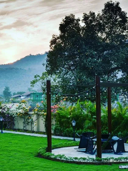 A beautiful sunset view from a landscaped plot, highlighting the seating area we designed under a simple wooden pergola. The addition of string lights creates a magical ambiance for evenings outdoors.