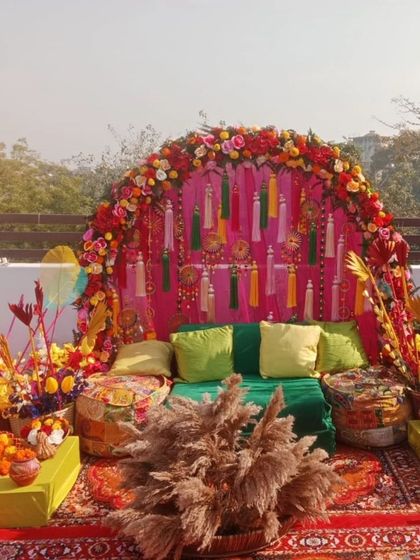 A perfect rooftop Mehandi setup with a vibrant, bohemian vibe. We used a floral arch, colourful tassels, low seating with gaddas, and lots of props for a festive and photogenic event.