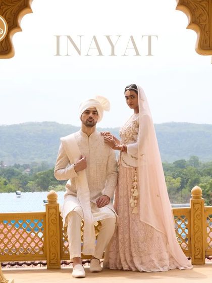 A majestic portrait of a couple, with the groom in a classic ivory sherwani from the Inayat collection. The intricate embroidery and luxurious fabric make it a perfect choice for a grand wedding.