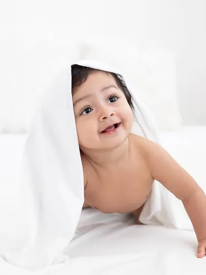 Peek-a-boo from under a white sheet. This playful shot is full of giggles and personality, perfect for a sitter session.