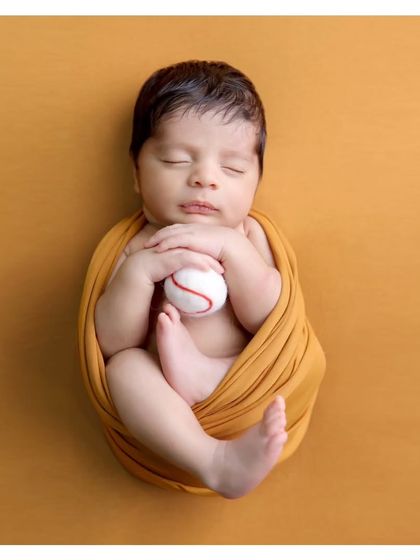 A simple and sweet portrait with a baseball prop. This classic swaddled pose is perfect for capturing the tiny details of your newborn.