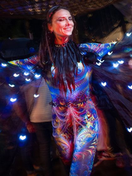 The performer smiles while wearing the illuminated cape, which features heart-shaped lights. We can customize the light patterns for different events and themes.