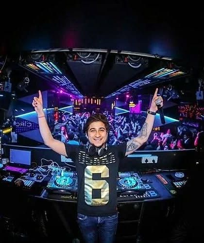 A wide-angle shot that captures the entire club experience. Me at the helm, the crowd fully engaged, and the incredible lighting and sound system of a premier nightclub.