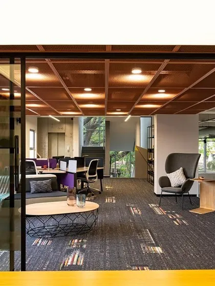 This view shows the conference room in context with the adjoining breakout space. The lighting design creates a clear distinction between the focused task area of the meeting room and the more relaxed ambient lighting of the lounge.