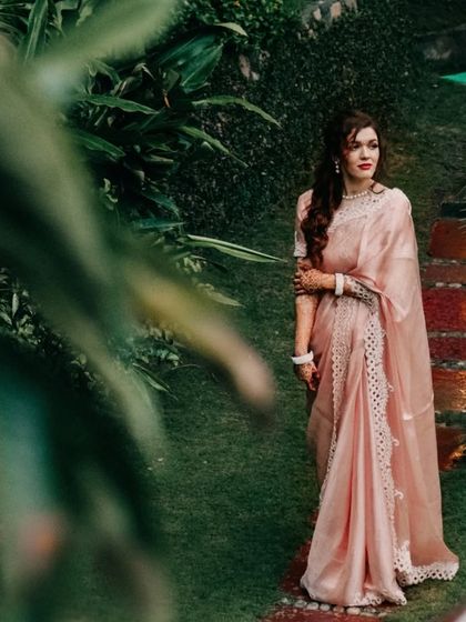 A solo portrait of the bride-to-be in a beautiful pink saree, captured in a lush garden setting during a mountain destination shoot.