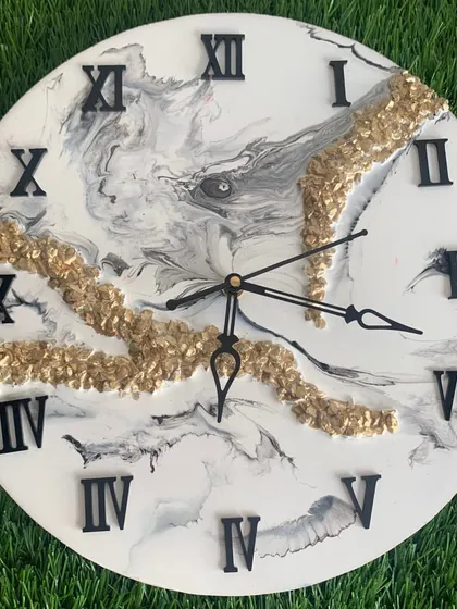 A close-up of the black and white marble clock, showing the intricate details and the texture of the gold crystal embellishments.