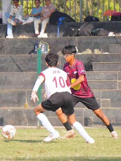 A player uses their body to shield the ball from an opponent, a key tactical skill.
