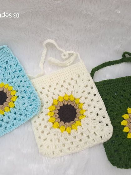 Here you can see the variety of colors available for my sunflower granny square sling bags. This photo shows the design in sky blue, off-white, and forest green.