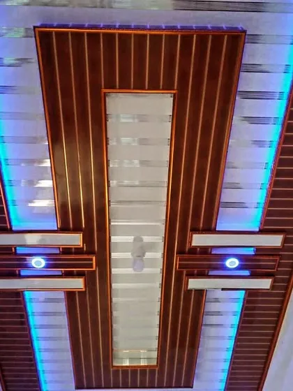 A bold, symmetrical PVC ceiling design with a dark wood finish. The bright blue side lighting creates a striking contrast and a very modern feel.