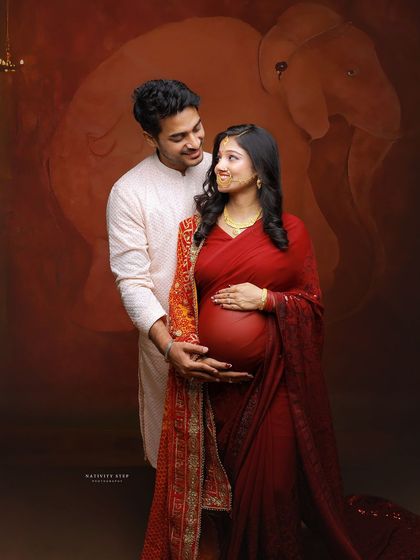 A beautiful couple's shot where the partner lovingly holds the baby bump. This pose beautifully captures their shared journey in a traditional setting.