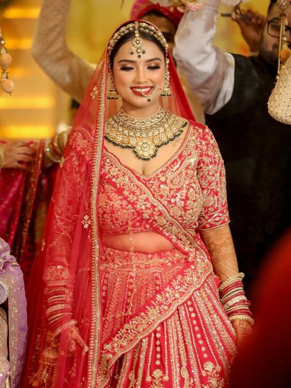 The happiness on a bride's face is my ultimate goal. This look was all about creating a radiant glow from within, with a classic red lip that perfectly matched her stunning bridal lehenga.