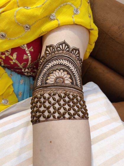 A clean and elegant arm band with a central floral mandala and a geometric jaal pattern below it.