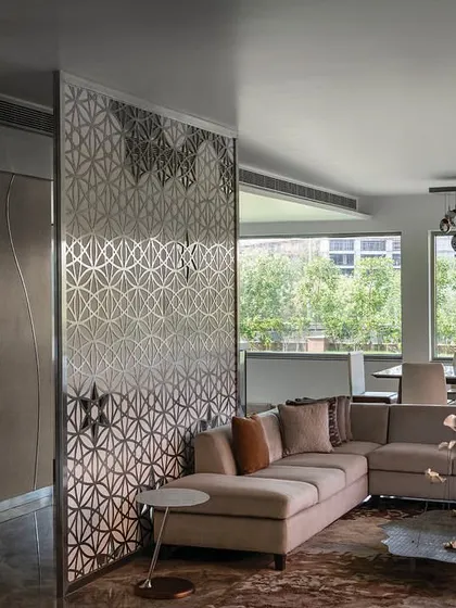 The director's lounge on the top floor of 'The Layered Office'. The space is defined by intricate stainless steel screens that create privacy while allowing light to pass through, connecting the lounge to the adjacent boardroom and terrace.