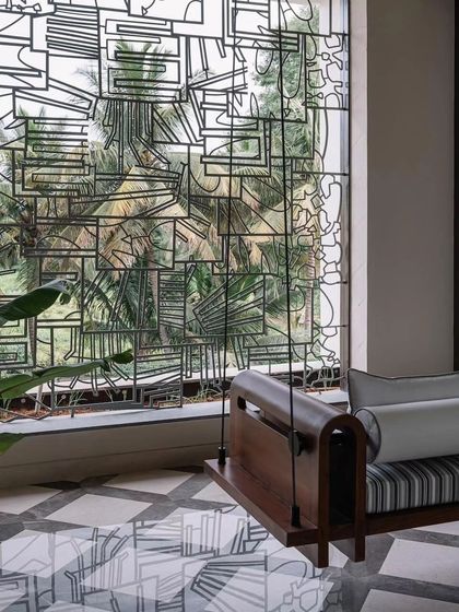 A closer look at the abstract metal window grill, revealing how its reflection on the polished floor becomes part of the artwork itself.
