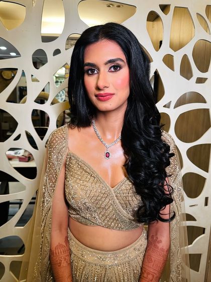 A radiant wedding guest with striking glittery eyes and glowing skin. The soft curls and modern lehenga create a chic and contemporary engagement party look.