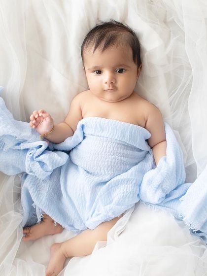 A simple and beautiful portrait of an alert newborn wrapped loosely in a blue blanket.