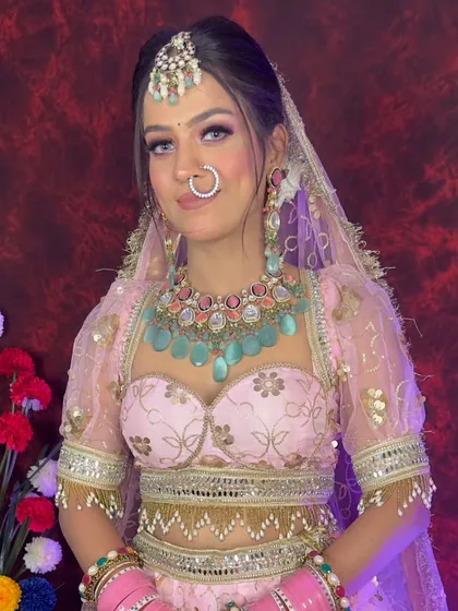 A bride in a baby pink lehenga with a pastel blue Kundan necklace. This soft, colorful look is ideal for a summer or daytime wedding ceremony.