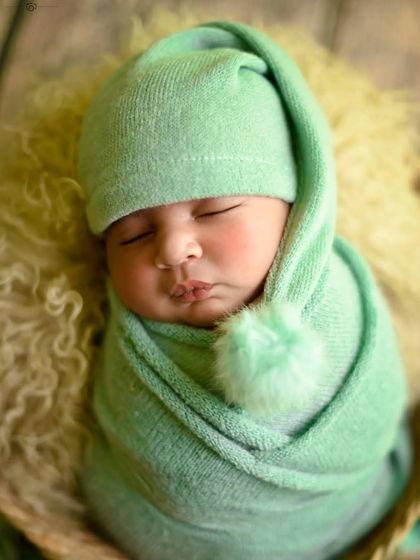 A detailed close-up of the baby's face, showing their perfect lips and nose, with a cute pom-pom hat.
