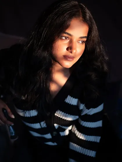 A quiet, contemplative portrait using shadows and light. The composition draws attention to the subject's thoughtful expression.